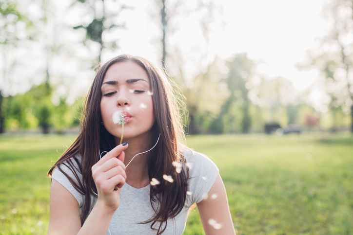 Girl blowing a dandelion in the park